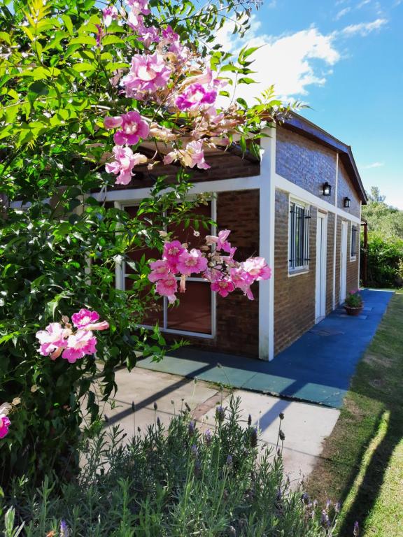 una casa con flores rosas delante de ella en La Algarroba en Alta Gracia