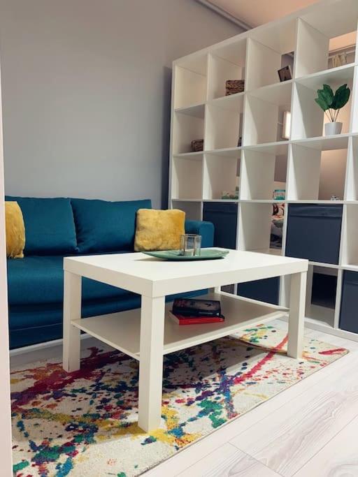 ein Wohnzimmer mit einem weißen Tisch und einem blauen Sofa in der Unterkunft Cozy Studio in Cluj-Napoca in Cluj-Napoca