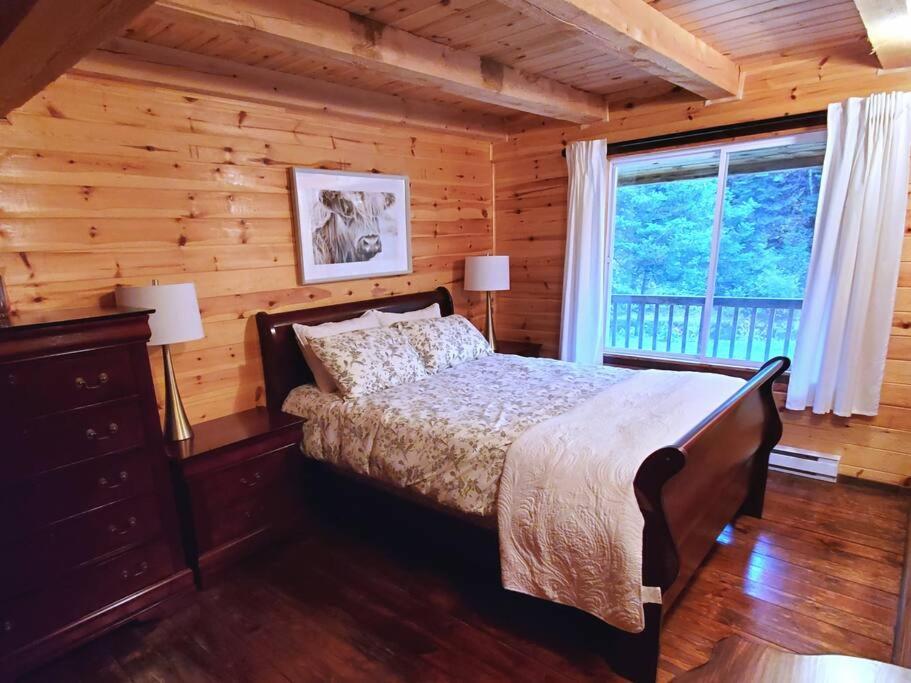 ein Schlafzimmer mit einem Bett in einem Blockhaus in der Unterkunft Chalet Rivière - Cozy - Bord de rivière - Petit déjeuner bio - Romantique in Saint-Alexis-des-Monts