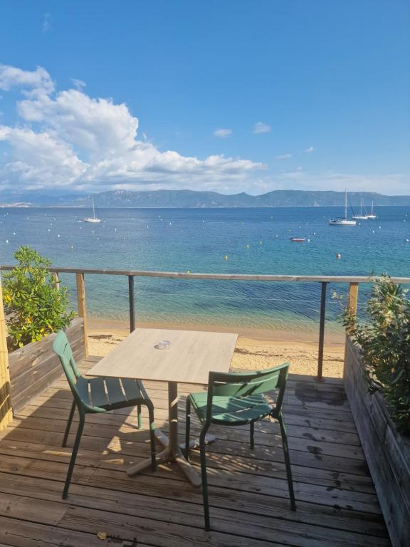 - une terrasse en bois avec une table et des chaises sur la plage dans l'établissement Hotel L'Escale, à Porto Pollo