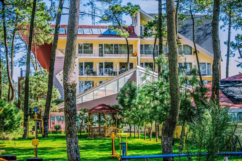 een groot geel gebouw met een speeltuin in een park bij Villa ReTa Hotel & SPA in Grigoleti