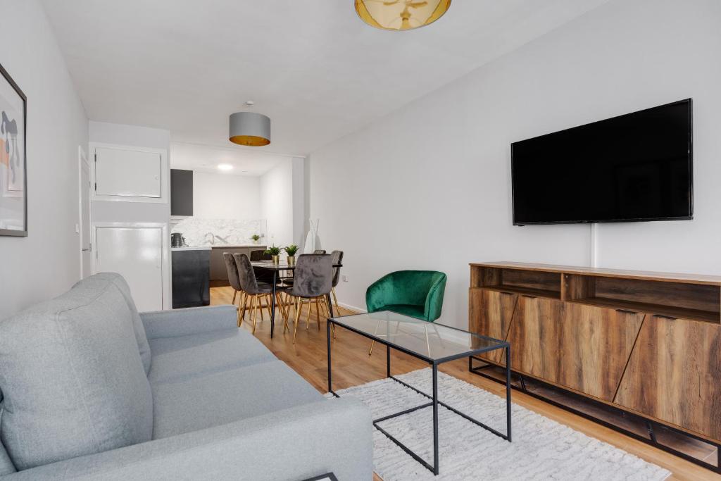a living room with a couch and a tv on a wall at Stanley St Suites By GuestFirst in Liverpool