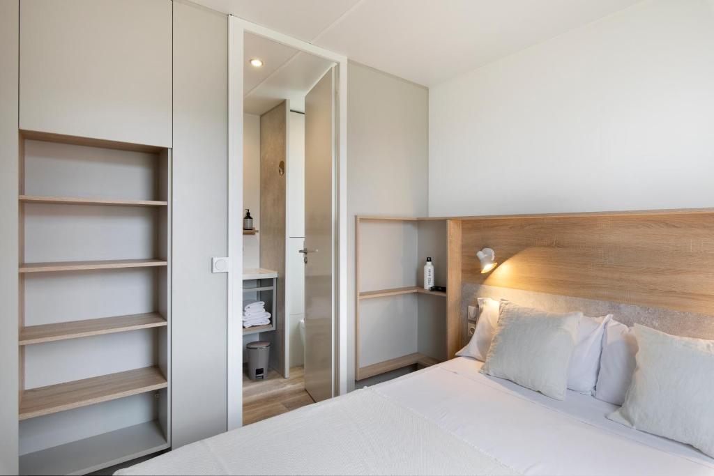 Schlafzimmer mit einem weißen Bett mit einem Kopfteil aus Holz in der Unterkunft wecamp Pirineos in Boltaña