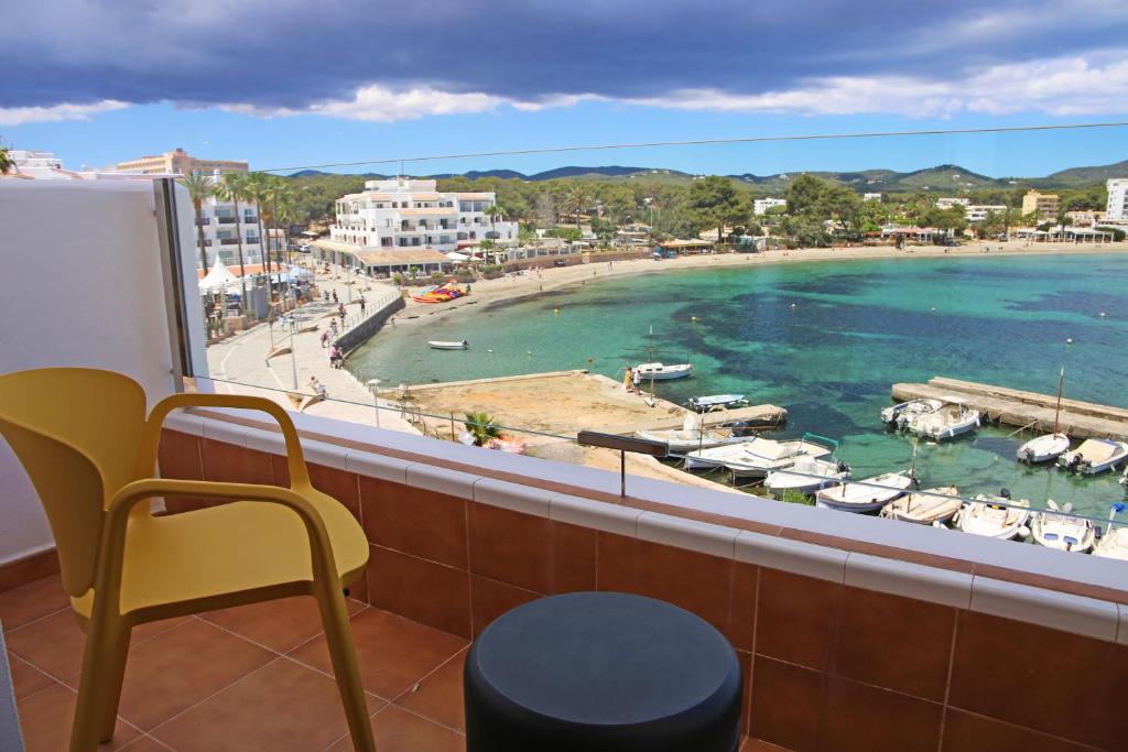 a balcony with a view of a beach with boats in the water at Apartamentos Playa Sol in Es Cana