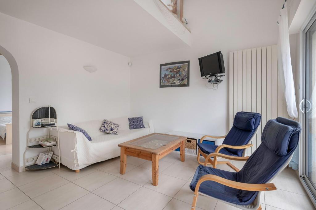 ein Wohnzimmer mit einem Sofa, einem Tisch und Stühlen in der Unterkunft Maison a trois cent metres de la plage in Saint-Nazaire