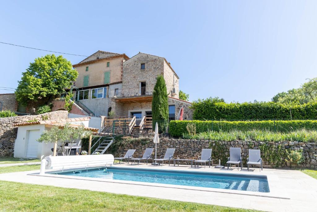 a pool with chairs and a house in the background at Maison de village in La Tour-sur-Orb