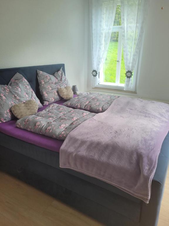 a bed with a purple comforter and a window at Ferienwohnung Rote-Villa 2 in Marienberg