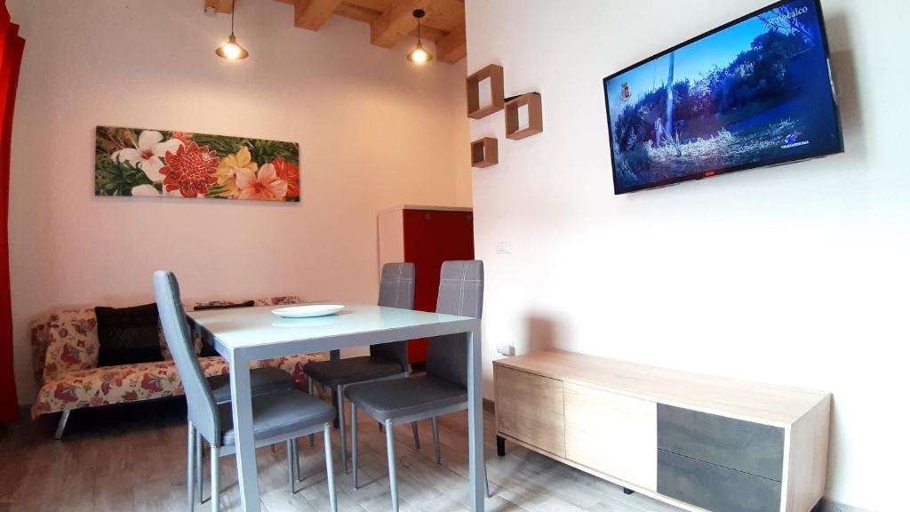 a dining room with a table and chairs and a tv at Casanuova Flat, City Center in Olbia