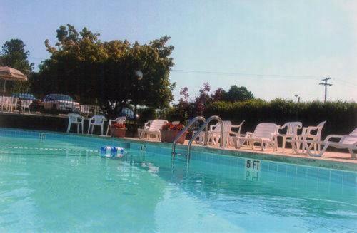 a swimming pool with white chairs and a slide in the water at Governors INN Shelby in Shelby