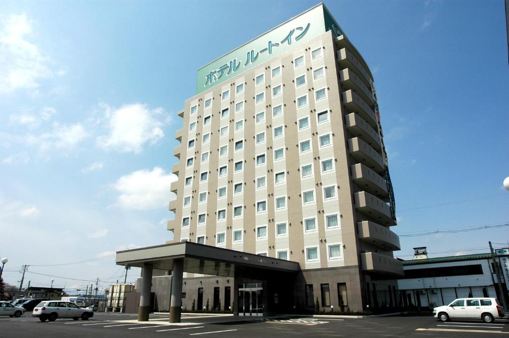 un grand bâtiment blanc avec un panneau sur celui-ci dans l'établissement Hotel Route-Inn Towada, à Towada