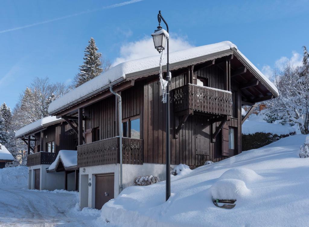 ein schneebedecktes Haus mit einer Laterne in der Unterkunft Chalet de Vantaa in Les Gets