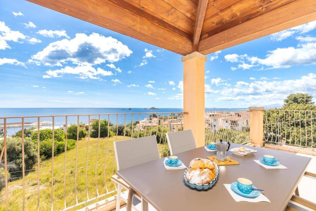 un tavolo e sedie su un balcone con vista sull'oceano di Appartamenti Flavia a Santa Maria Navarrese