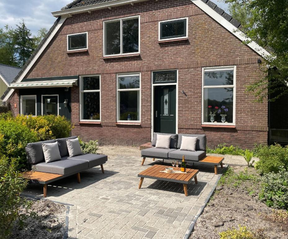 une terrasse avec des canapés et des tables en face d'une maison en briques dans l'établissement Appartement Elperhof 16A, à Schoonloo