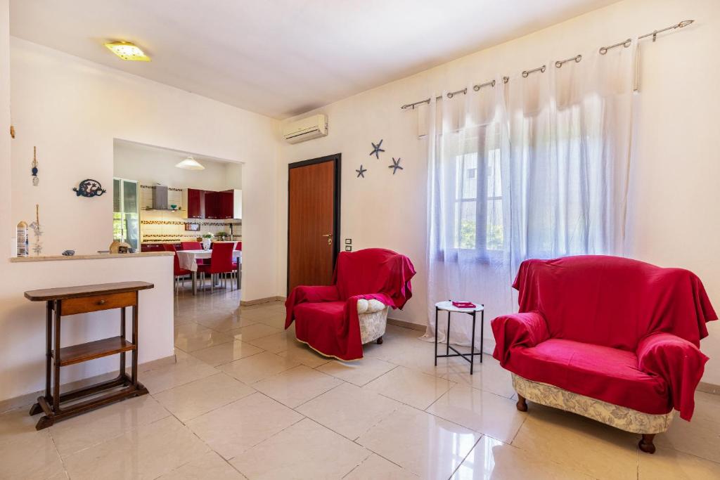 a living room with red chairs and a table at Casa Marina in Rosolina