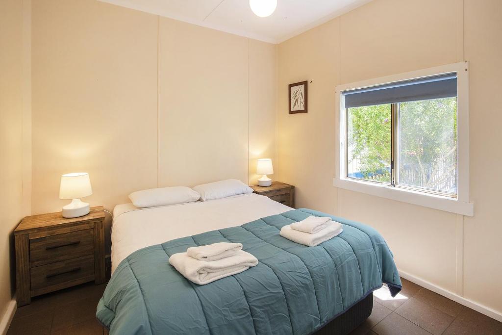 a bedroom with a bed with two towels on it at Riverscape Cottages in Augusta