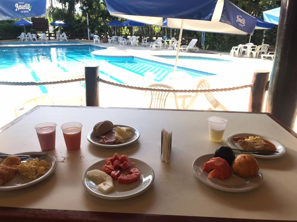 a table topped with plates of food next to a pool at Riviera de São Lourenço - 302 Amarilis in Bertioga