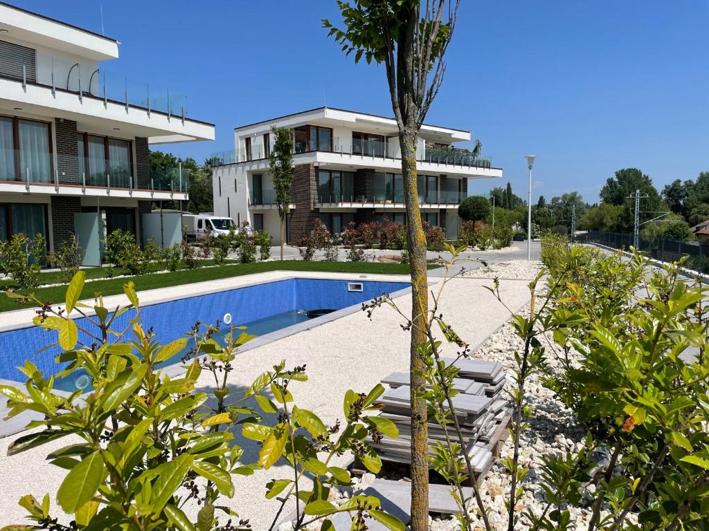 a resort with a palm tree in front of a building at Panorama Superior Apartments - Pool, garden, parking in Balatonalmádi