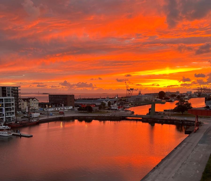 einen Sonnenuntergang über einem Wasserkörper mit einer Stadt in der Unterkunft COAST HOUSE Seaside Loft in Bremerhaven