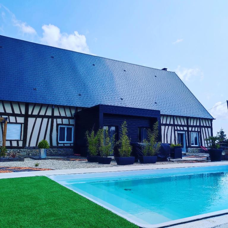 a house with a swimming pool in front of a building at Le clos des crins in Pavilly