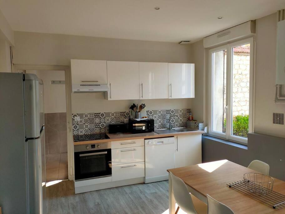 a kitchen with white cabinets and a wooden table and a table and a tableearcher at Venise - Maison avec extérieur à Reims in Reims