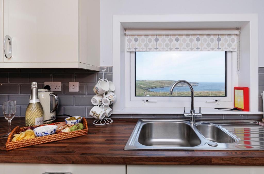 a kitchen counter with a sink and a window at Coleil Cottage in Garrabost