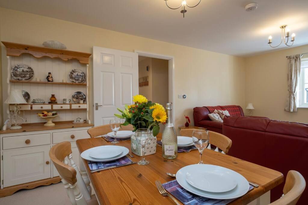 a dining room with a table with plates and flowers on it at Cosy coach house in historical Tetbury in Tetbury