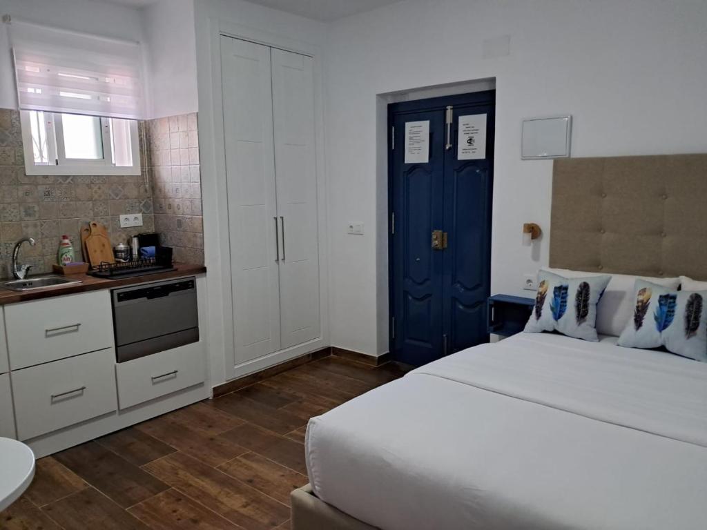 1 dormitorio con 1 cama grande y puerta azul en Casa Vladimir en Arcos de la Frontera
