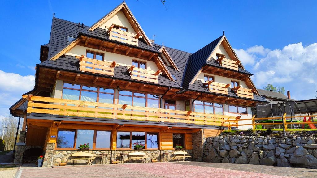 a large wooden house with people on the balcony at Willa Adamówka in Zakopane