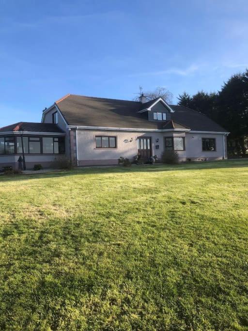 una gran casa blanca con un gran campo de césped en Meadow House in County Donegal, en Donegal