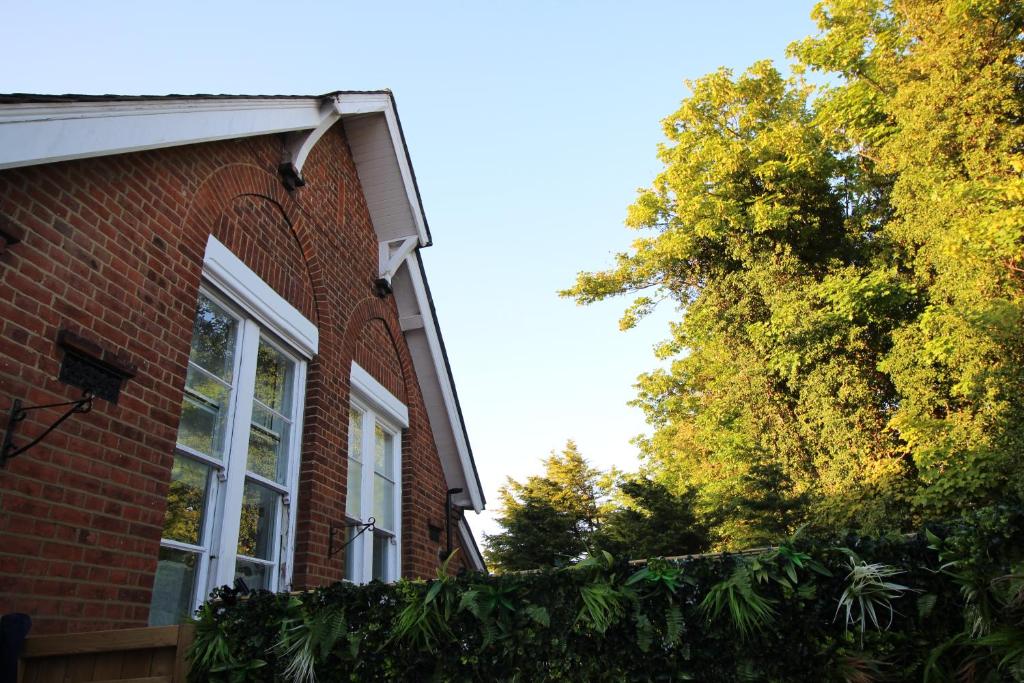 a brick house with a window and a hedge at The Old Schoolhouse in Whitstable