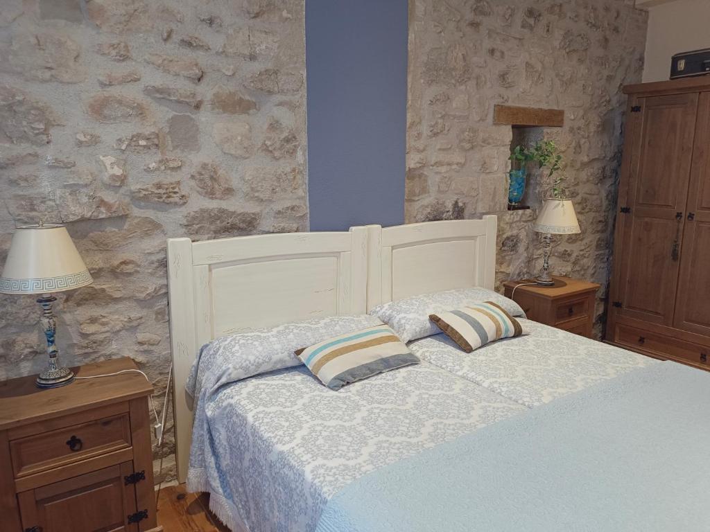 オリテにあるRonda del Castilloのベッドルーム1室(ランプ2つ、石壁付)