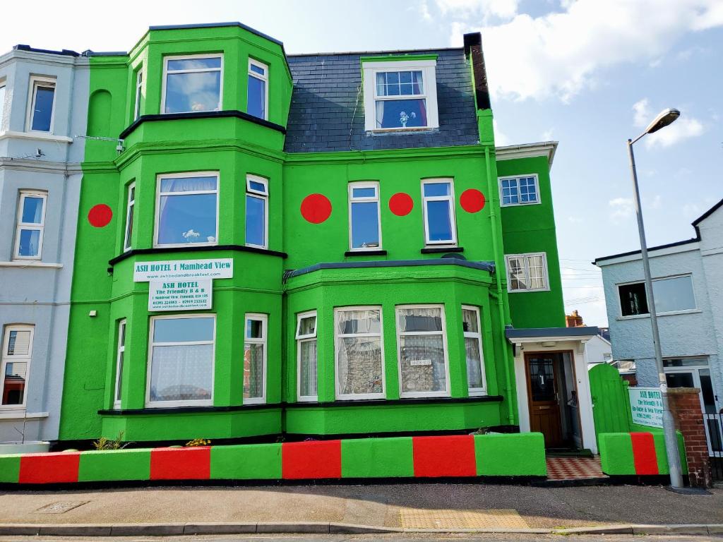 Ash Hotel B&B في اكسماوث: مبنى أخضر عليه صبغ احمر وأخضر