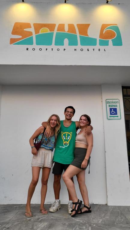 a group of three people standing in front of a wall at Sohla Rooftop Hostel in San Juan del Sur