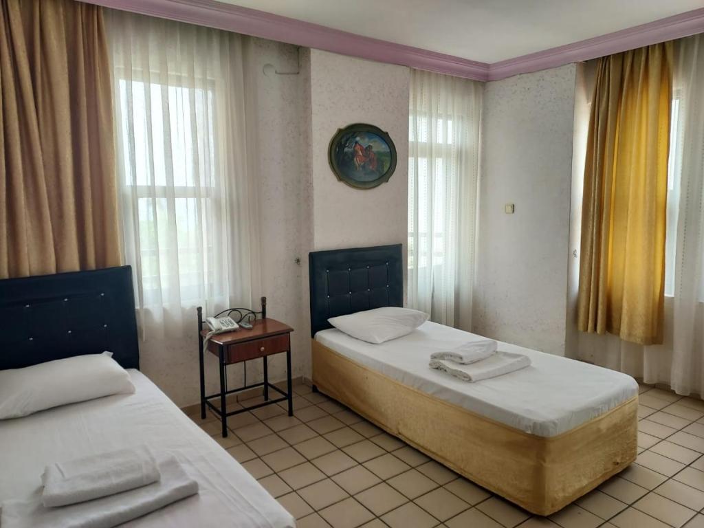 a bedroom with two beds and a table and windows at Kleopatra Sahara Hotel in Alanya