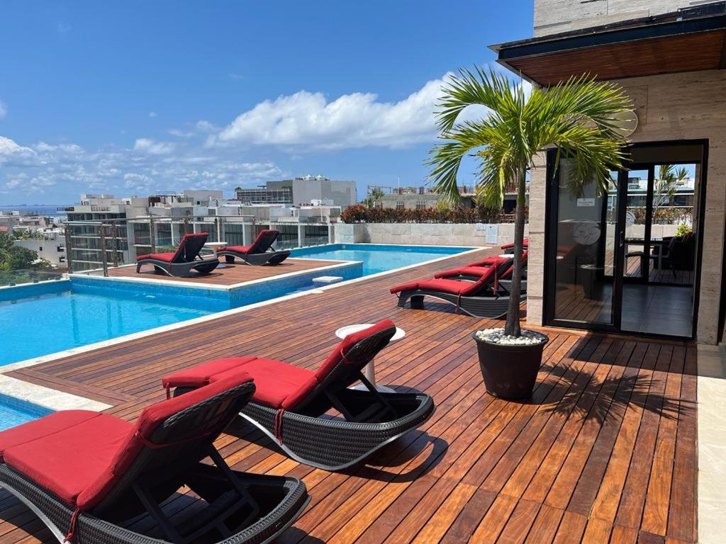 een terras met ligstoelen naast een zwembad bij Grand Fifty Suites in Playa del Carmen