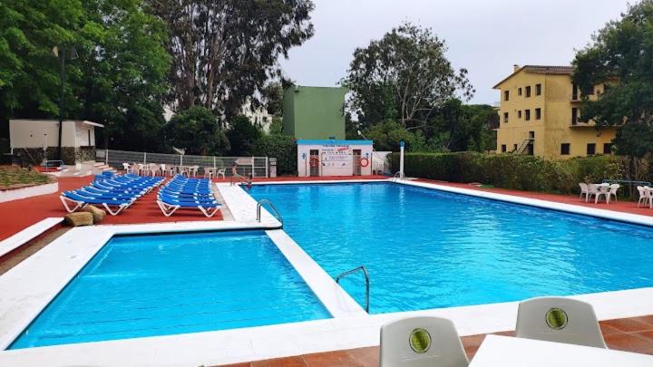 een groot zwembad met blauwe stoelen en een gebouw bij Playa de Aro in Platja  d'Aro