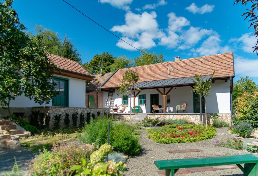 a cottage with a garden and a green bench at Alsópetényi Vendégházak in Alsópetény