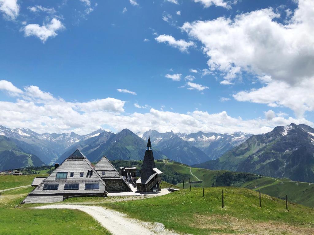 a church on a hill with mountains in the background at Schneekarhütte in Mayrhofen