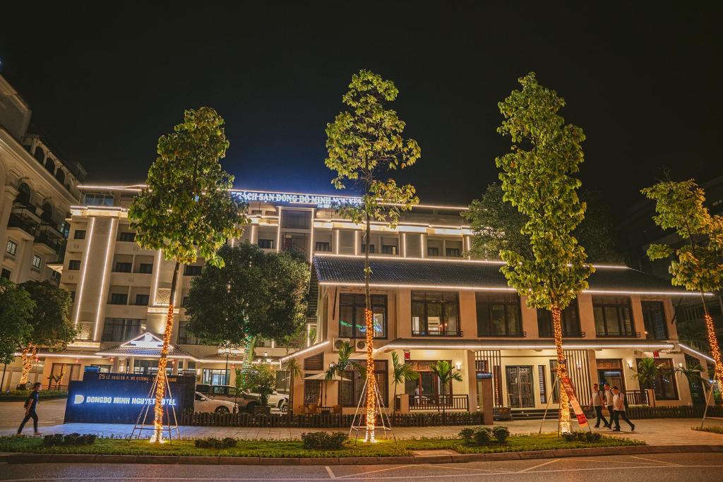 un edificio con árboles delante de él por la noche en 东都明月酒店Dong Do Minh Nguyet, en Bồ Sơn