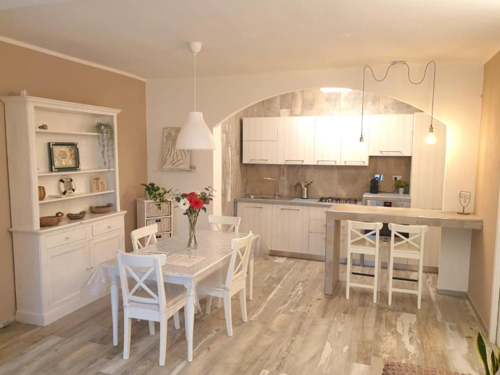 eine Küche mit einem Tisch und Stühlen sowie eine Küche mit weißen Schränken in der Unterkunft Appartamento Dea in Marina di Campo