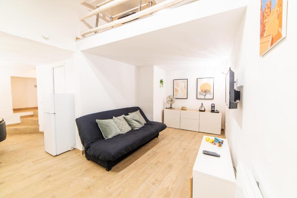 - un salon avec un canapé noir dans une pièce blanche dans l'établissement Ou Mentounasc - Duplex Vieille Ville Menton - Free Parking, à Menton