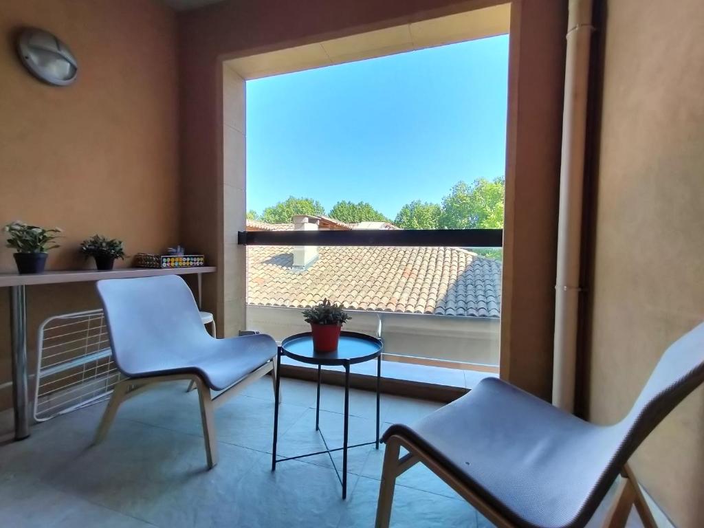 2 chaises et une table dans une chambre avec une grande fenêtre dans l'établissement ALLEES PROVENCALES 2, à Aix-en-Provence