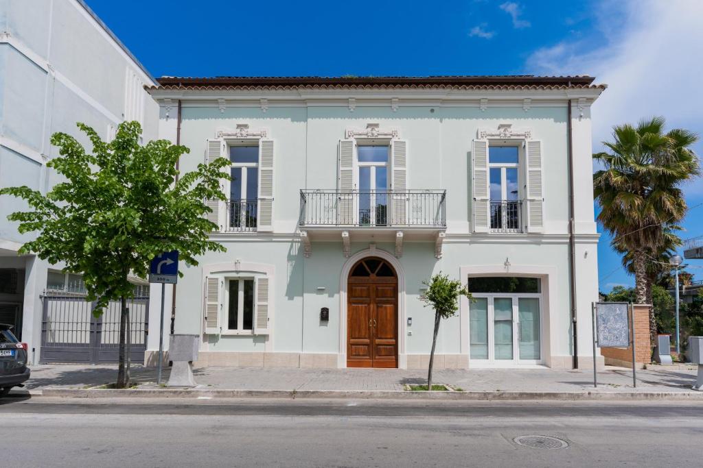 a white house with a brown door on a street at Villa Gina Case Vacanze in Roseto degli Abruzzi