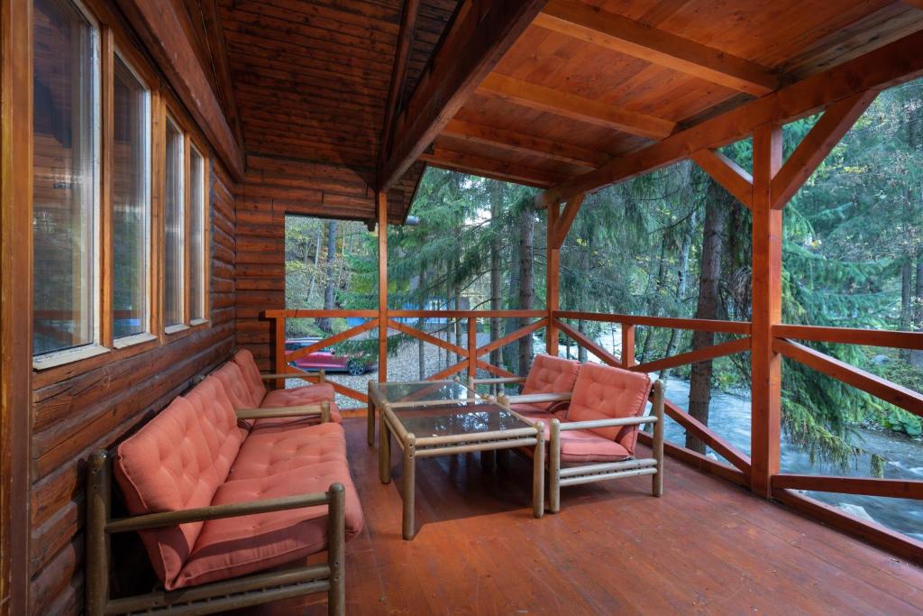 un porche de una cabaña con 2 sillas y una mesa en TATRYSTAY Chalet Kristina en Demanovska Dolina
