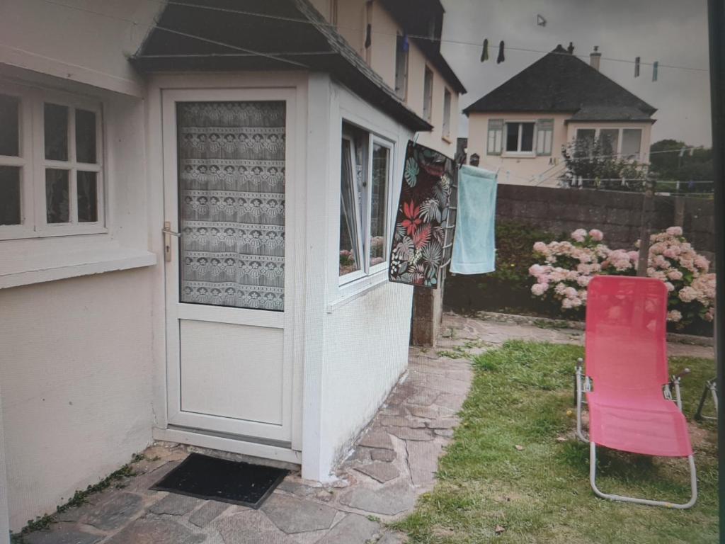 una silla roja sentada fuera de una casa con una puerta en Studio Madeleine "endroit calme" en Morlaix