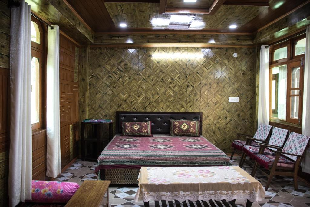 a bedroom with a bed in a room with chairs at Aaruhee Homestay in Kalpa