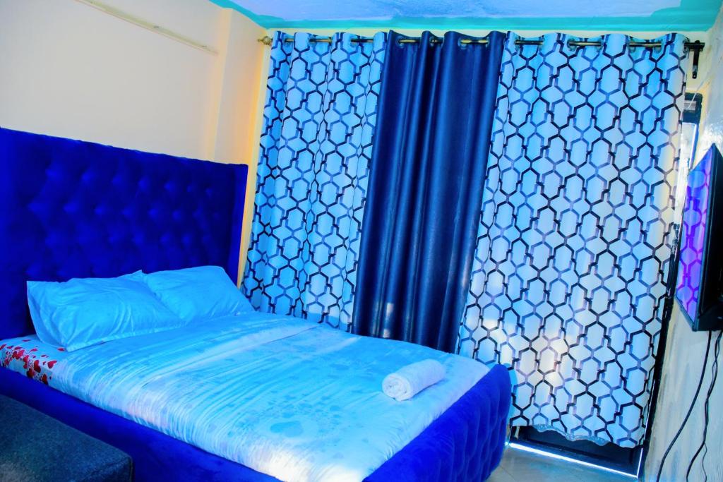 a bedroom with a blue bed with a blue curtain at Sweet homes in Nairobi