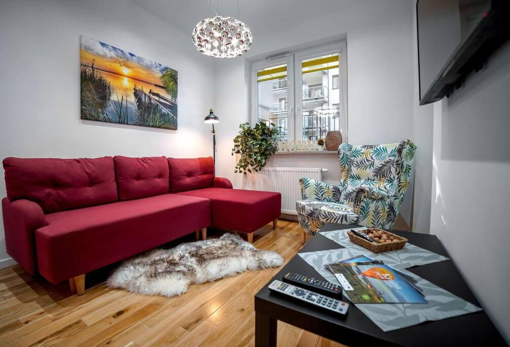 a living room with a red couch and a table at Nowoczesny dwupokojowy Apartament Bridget z parkingiem in Ełk
