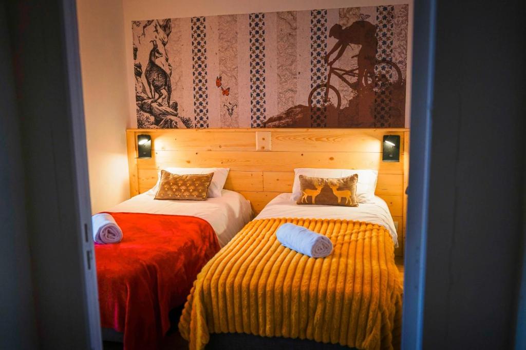 sypialnia z 2 łóżkami z czerwoną i żółtą pościelą w obiekcie LE PETIT CERF w mieście Cervières