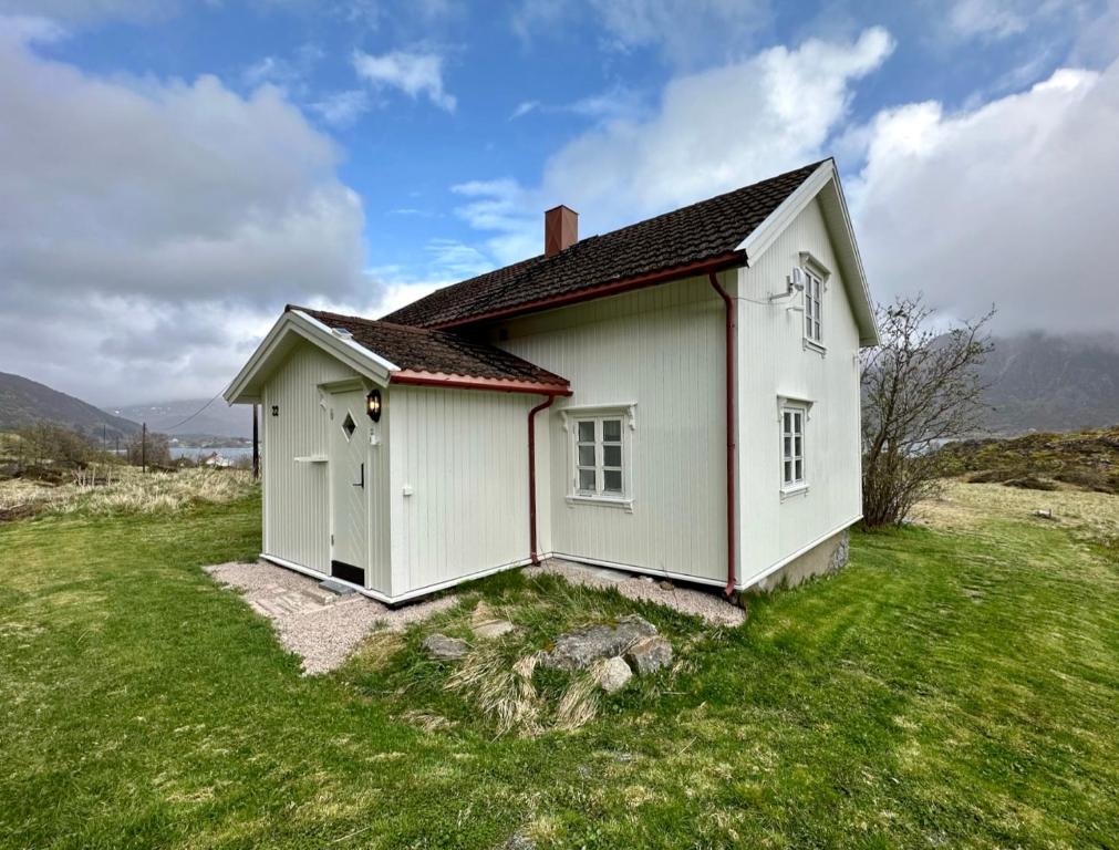 a small white house in a field of grass at Storhella - Feriehus med fantastisk beliggenhet in Sennesvik